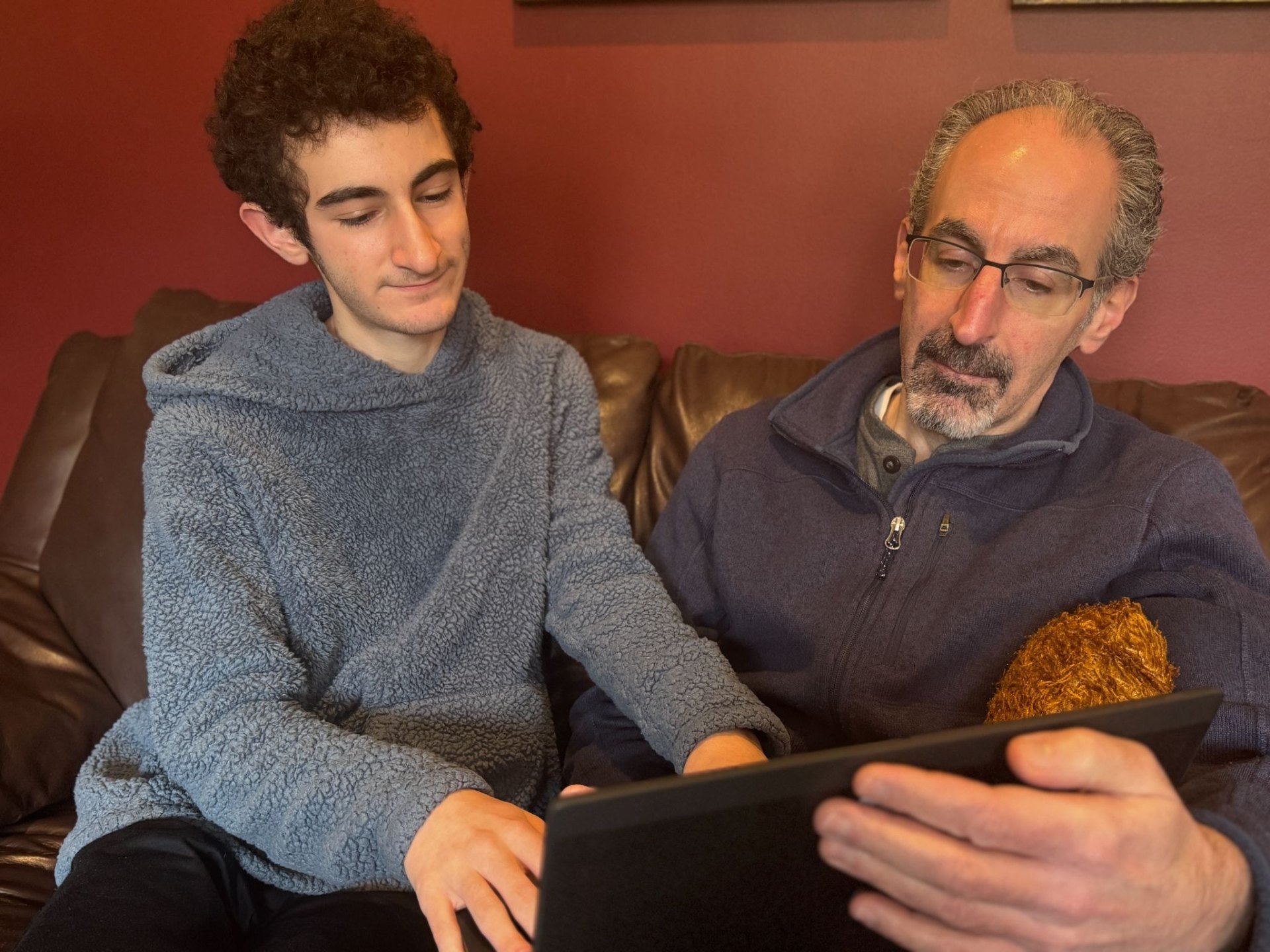 Friendly, patient tech help — a student helping a neighbor with a laptop